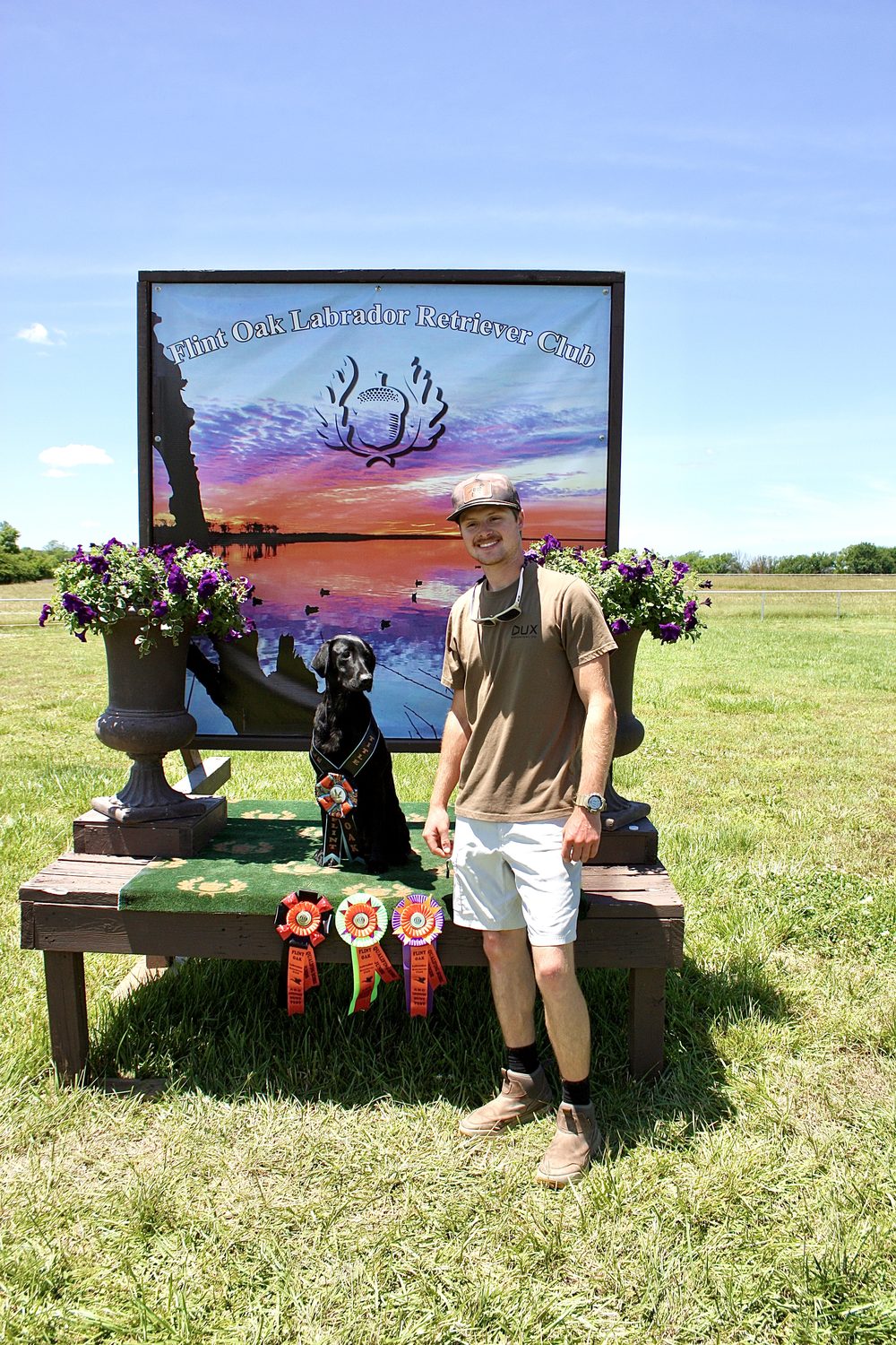 Devin with a black Labrador and award ribbons